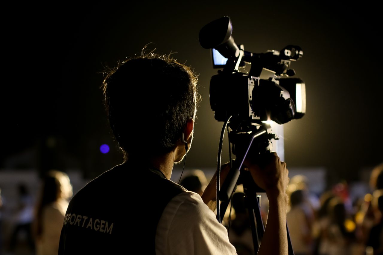 Crafting Captivating Headlines: Your awesome post title goes here A cameraman filming an event outdoors at night with professional equipment, capturing the vibrant atmosphere.