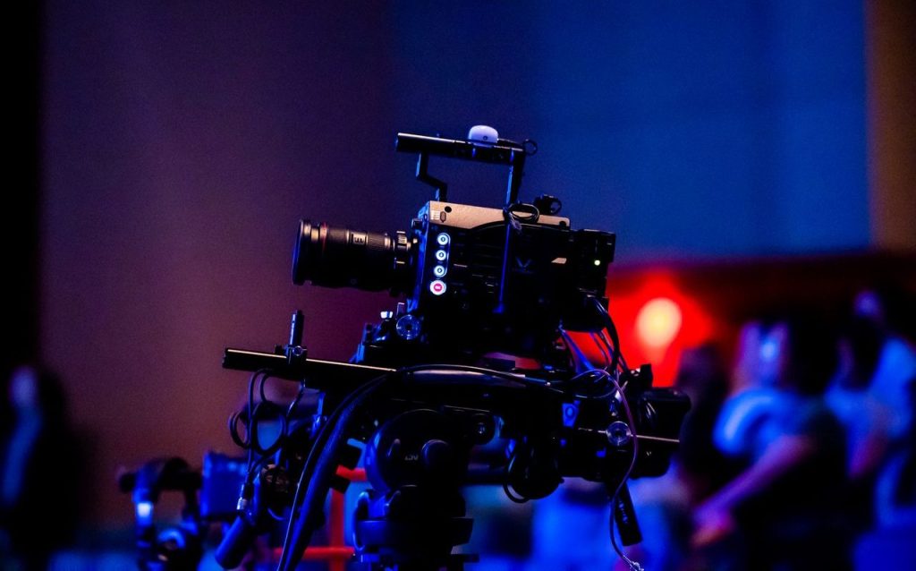 About A high-quality camera setup capturing a live studio event with an audience in the background.